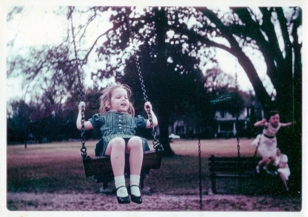 A young girl swinging on a swing set. 