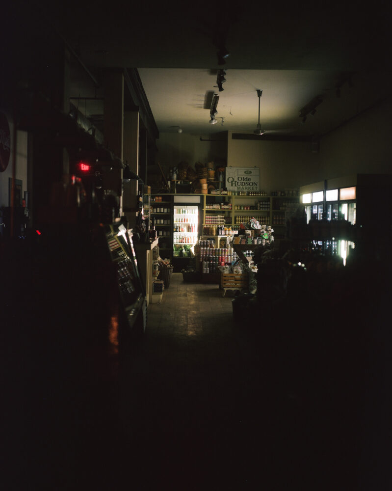 Photograph depicting the inside of a bodega lit up at night by a few inner lights