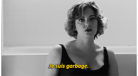 A woman, looking into the camera with the caption: "je suis garbage"