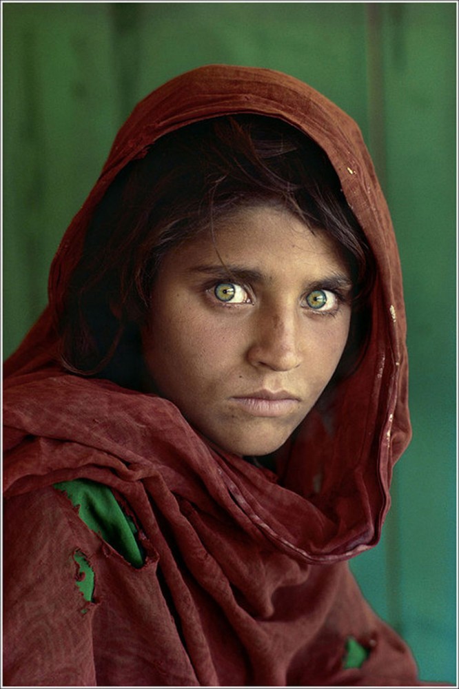 Portrait of Sharbat Gula, a girl with bright green eyes and a red headscarf. 