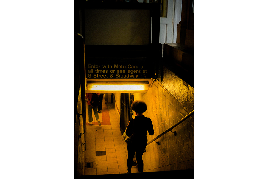 A woman walking into the 8th Street & Broadway station at night