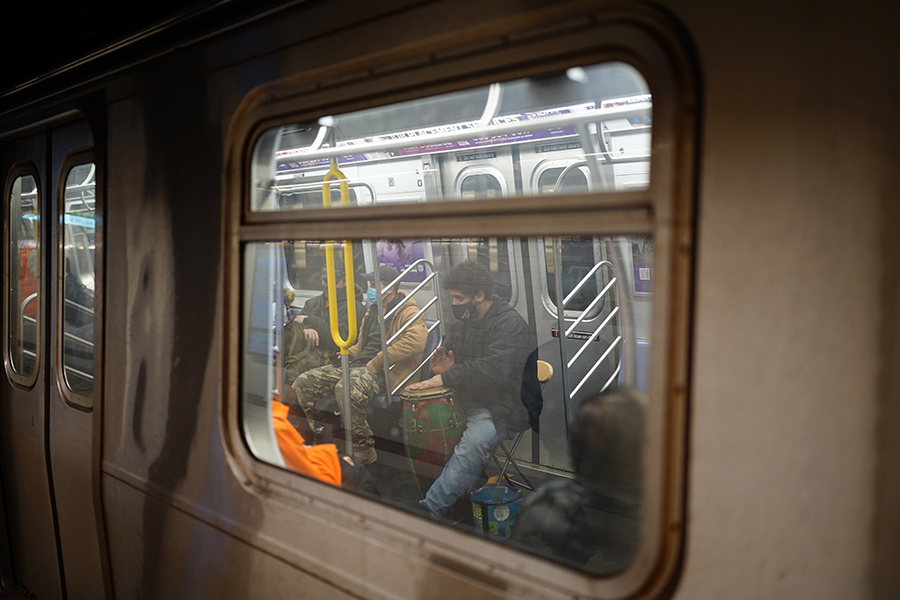 A drum performer in a train seen through the train’s window
