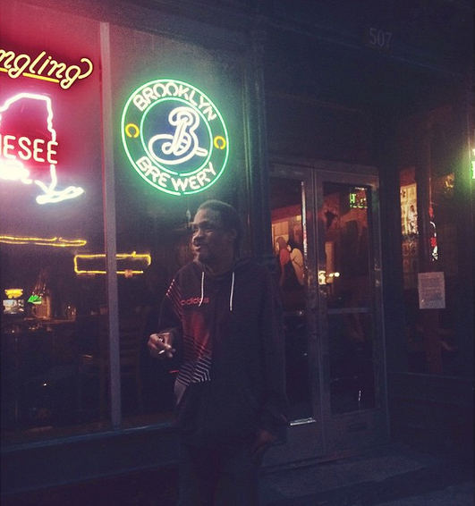 Man standing in front of a neon "Brooklyn Brewery" sign. 