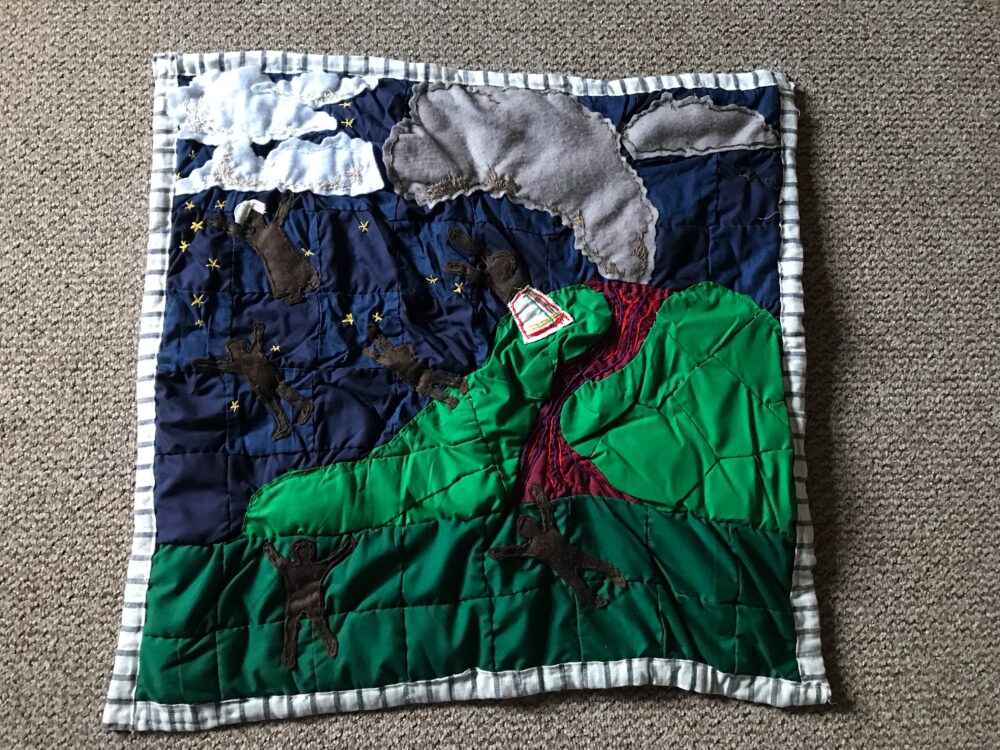An overhead view of the volcano quilt: dark figures, the enslaved, take flight against the backdrop of an erupting volcano.