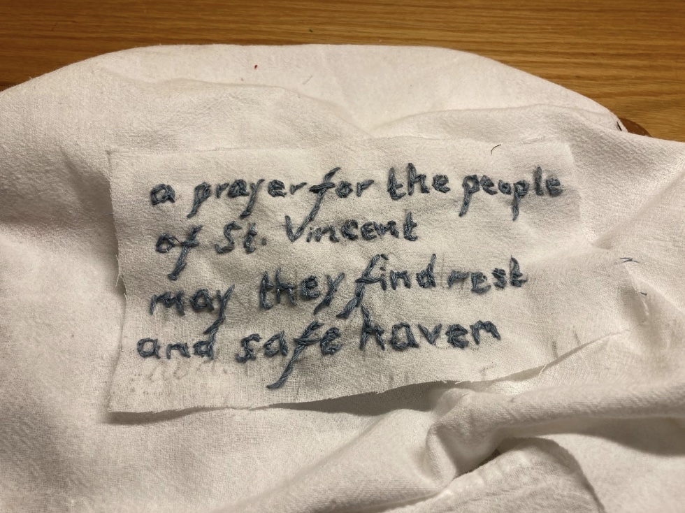 A small piece of fabric reading "a prayer for the people of St. Vincent / may they find rest and safe haven."