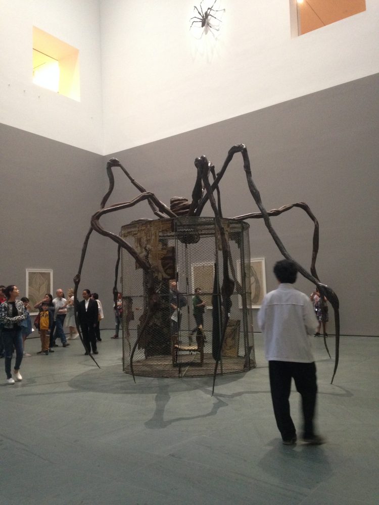 A sculpture of a spider cage: a steel cage structure with protruding legs resembling a spider's.