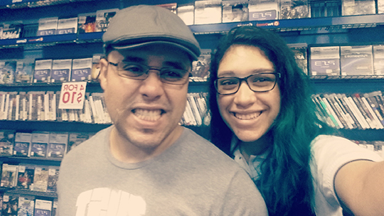 A selfie of the author, now a teenager, and her father, in a video store; racks of DVDs and video games are visible in the background