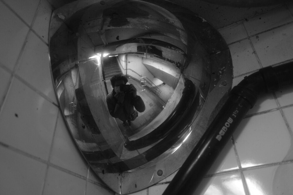 Self portrait in the reflection of a corner mirror in the subway