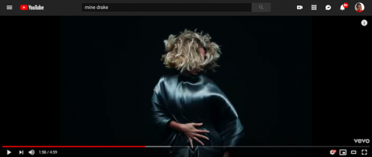 A screengrab of the music video shows Beyonce against a black background in blond cropped hair covering her face with her body covered in shiny blue cloth that she presses to her body.
