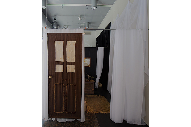Large white sheets hanging from bars, one painted with the image of a door. 