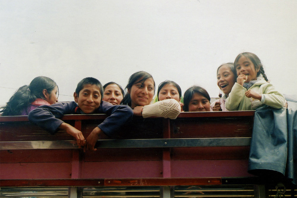 A group of people gazing toward the camera: some kids (eating, laughing), some older. 