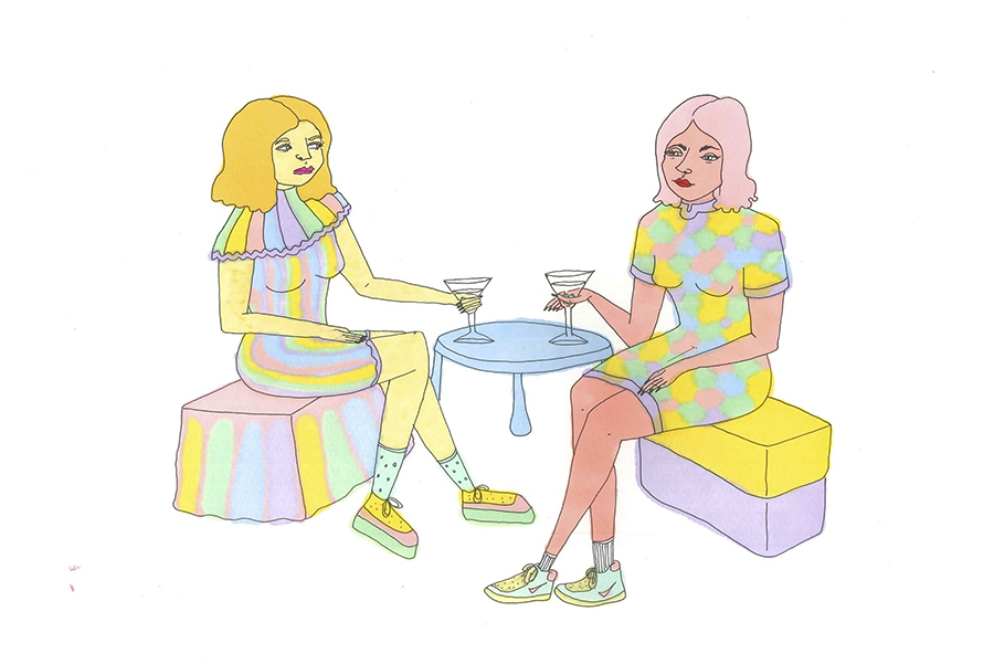 Two women in pastel outfits sit on pastel benches and hold martini glasses propped on a small, circular table between them