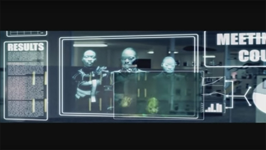 Three authorities, who appear robot-like, look through a glass scrim at the smaller scrim on which Asha's dream is displayed