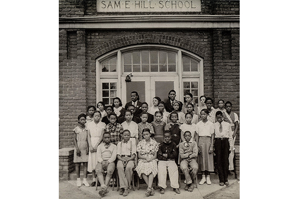 A class photograph outside a brick school building