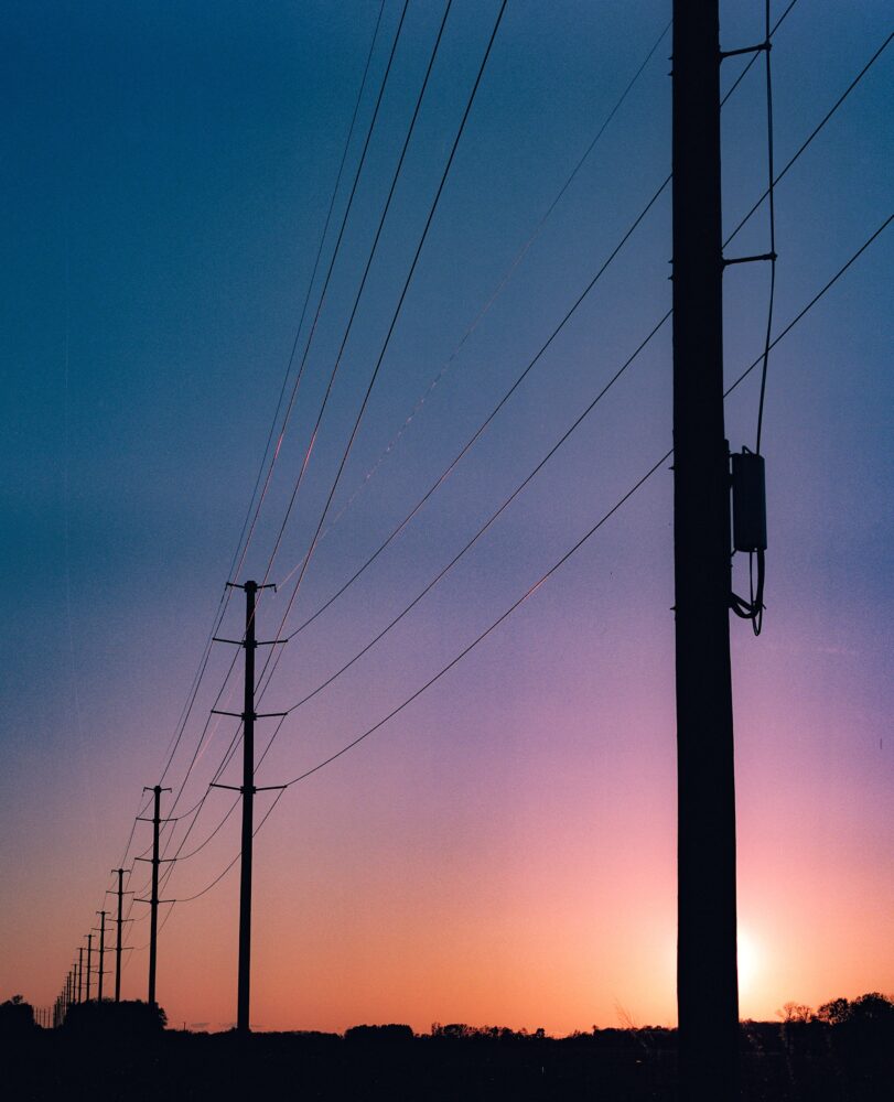 Picture depicting telephone poles just as the sun inches past the horizon