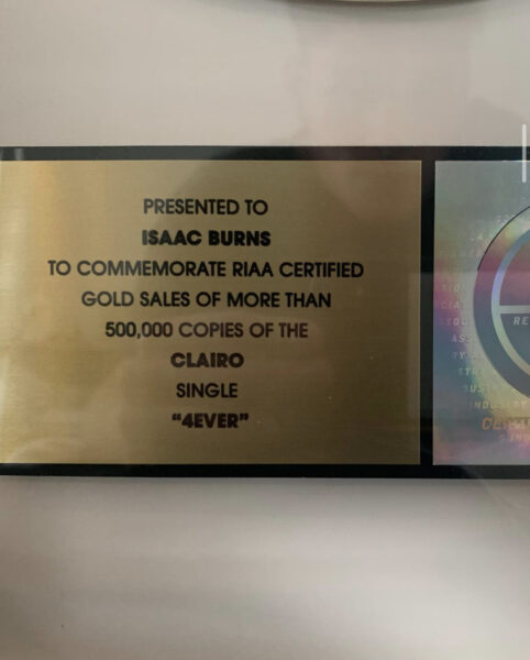 Enhanced shot of the text on Iz’s certification plaque, reading: “Presented to Isaac Burns to commemorate RIAA Certified Gold Sales of more than 500,000 copies of the Clairo single 4Ever.”