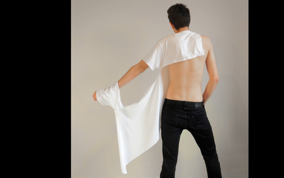 Model shows the back of the shirt: the top of the back is covered by white fabric, the sleeve hanging down from its attachment on the wrist. 
