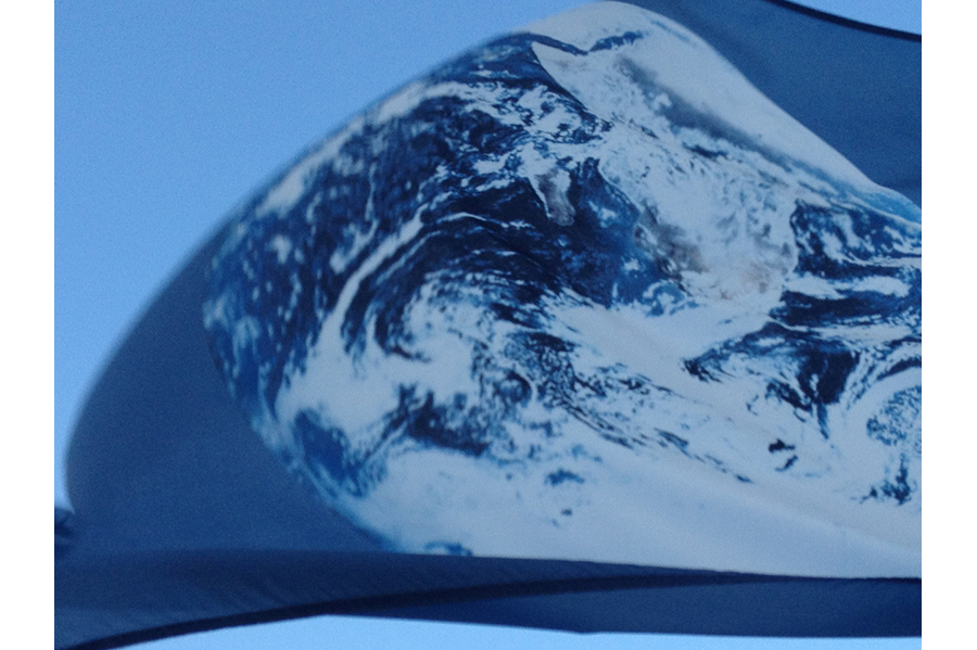 Close-up of an Earth flag flying in the wind, the planet filling the frame. 