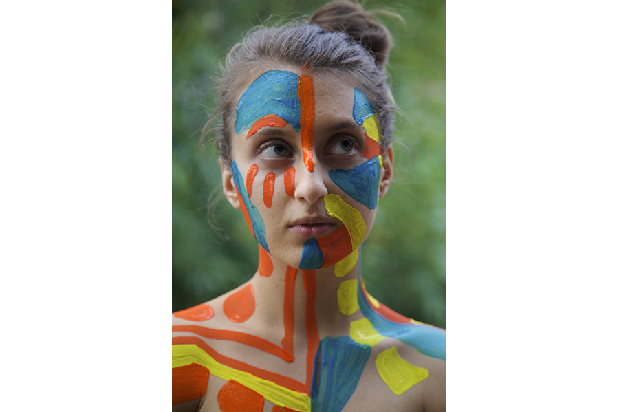 A portrait of woman with blue, orange and yellow paint.