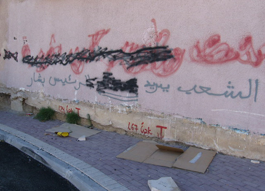 Covered graffiti in Arabic, made to read “The People Want President Bashar.”