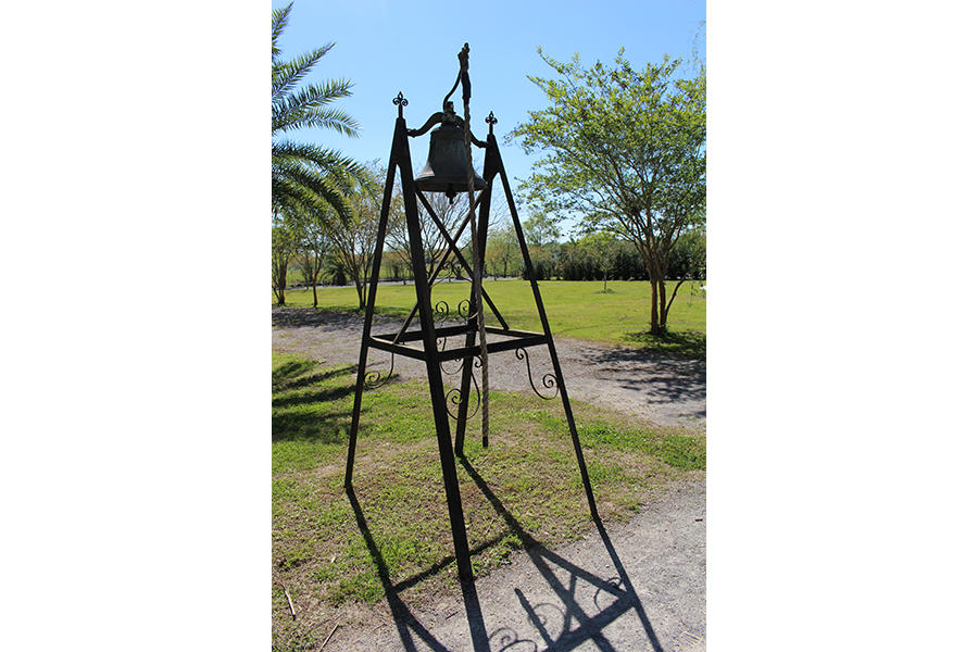 A tall, looming bell casts its shadow across the dirt path that leads to the Field of Angels. Though simple at first glance, the bell’s tower has elegant, swirling accents, and is tipped with fleur-de-lis. A thick rope connected to an arm extending from the top of the bell reaches for the ground. 