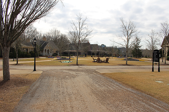 A wide path encircles a large lawn, on which are reclining chairs and other signs of recreation