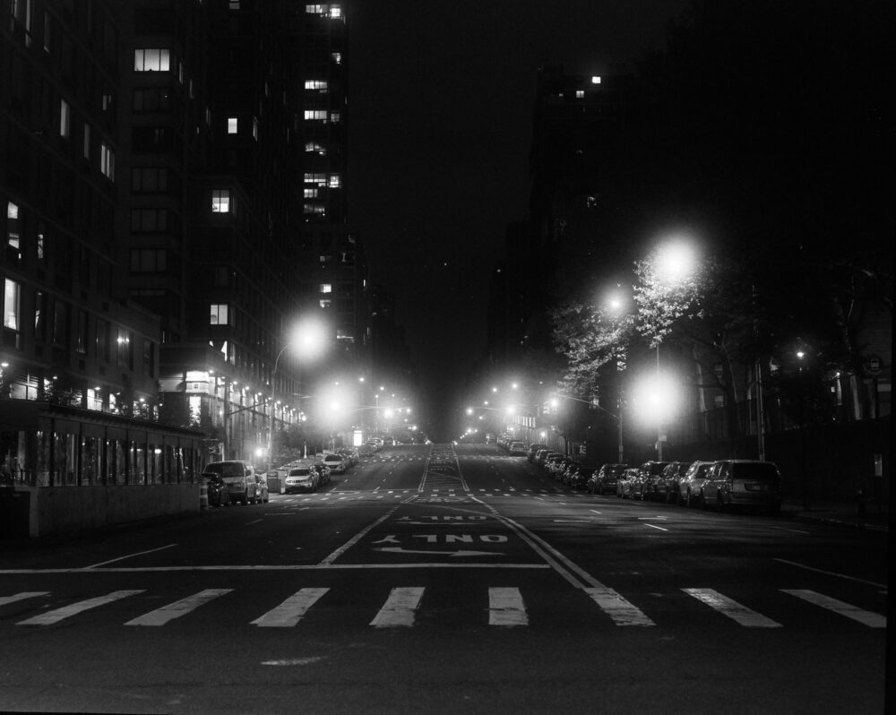 Photograph depicting an empty street at night, only lit by street lamps