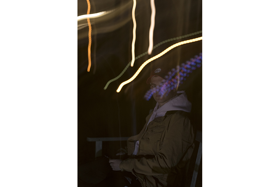 Photograph of streaked lights, seated figure in background