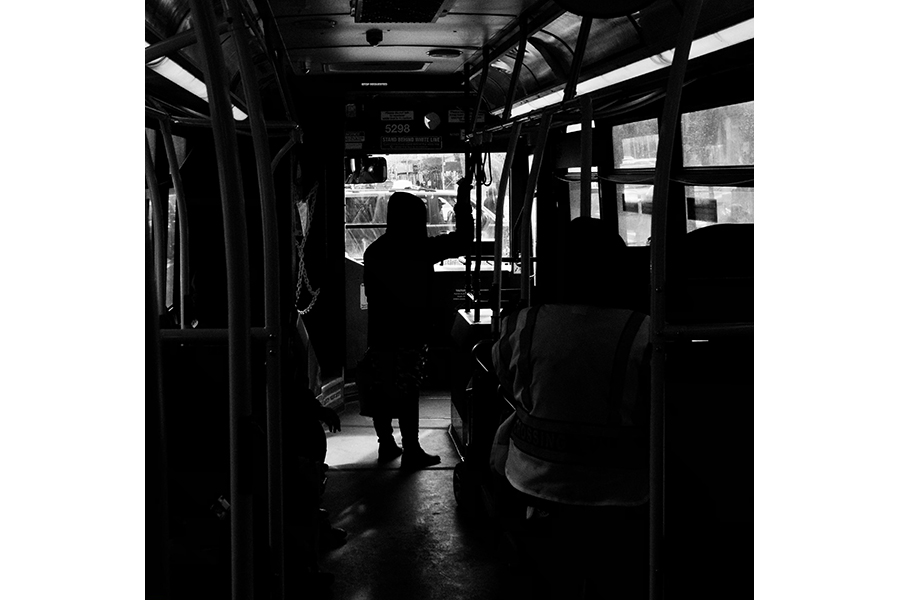 The silhouette of a person standing at the front of a Bronx bus. 