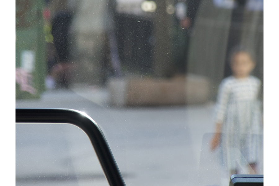 In Harlem, a slightly out of focus child is seen through the lower right-side of the bus’s front windshield. 