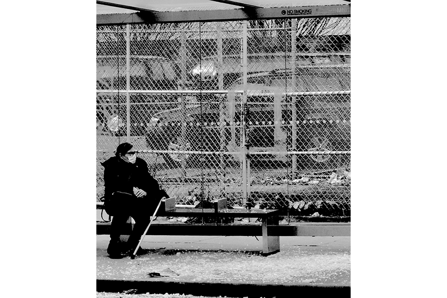Portrait of a stranger with shaded eyes, sitting at a Harlem bus stop.