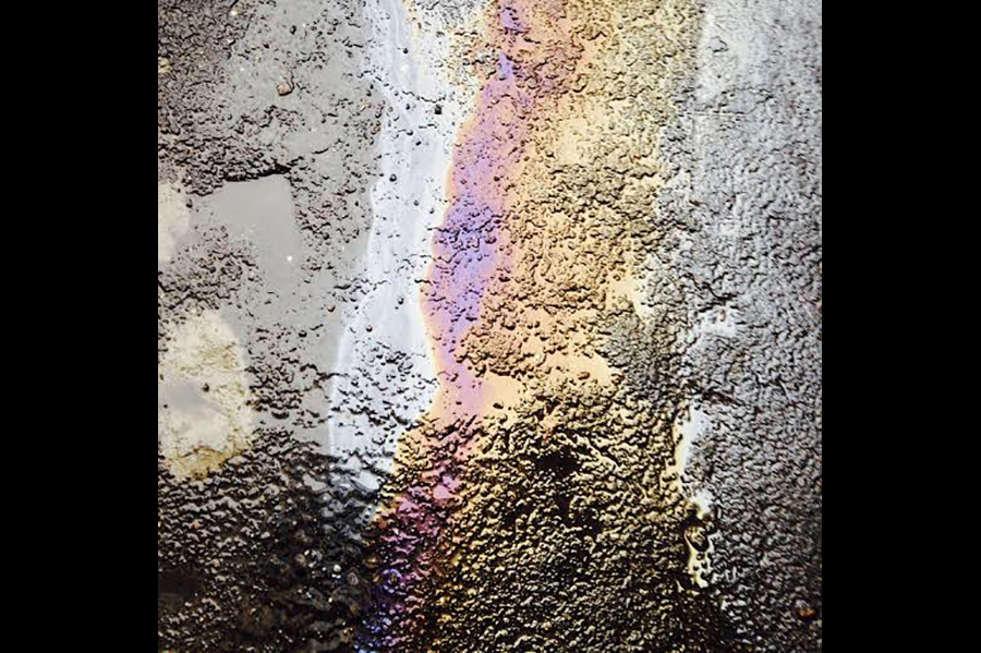Close-up of a puddle on a road with a mixture of water and oil creating a colorful reflection.