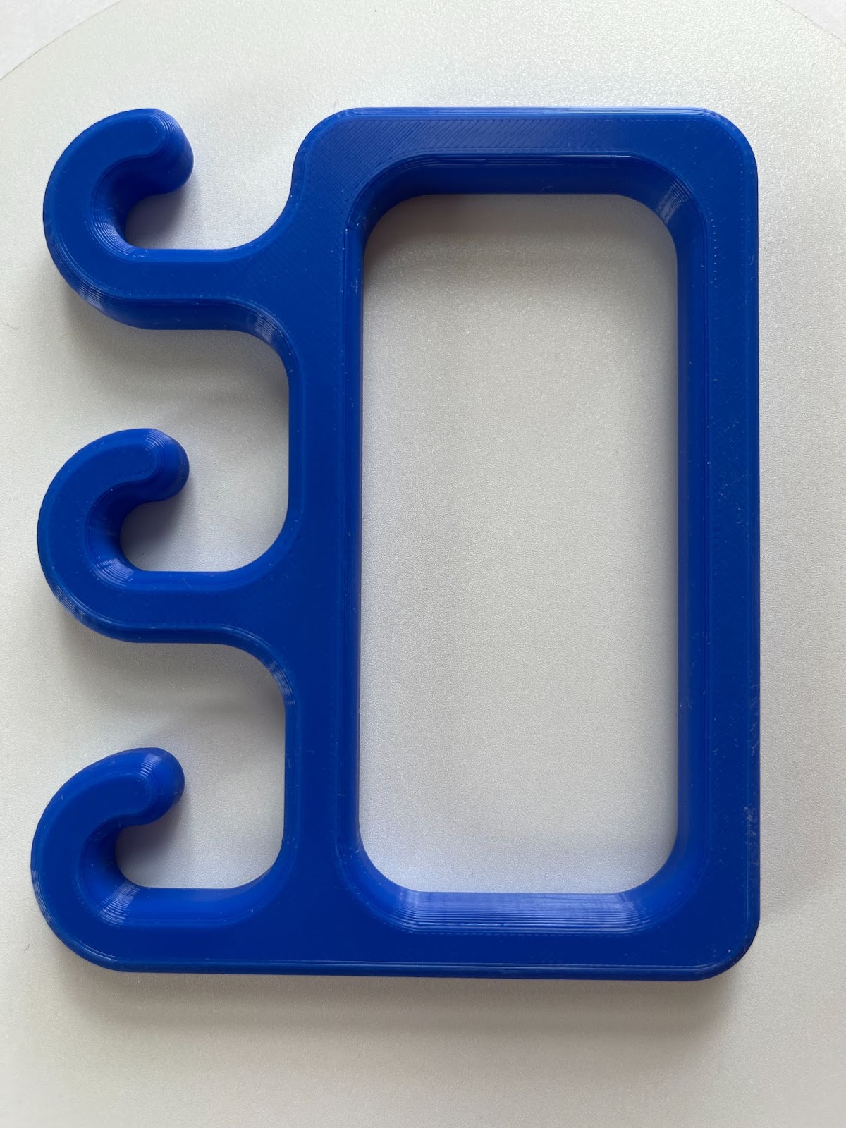 A blue, 3D printed handle with three hooks on the bottom