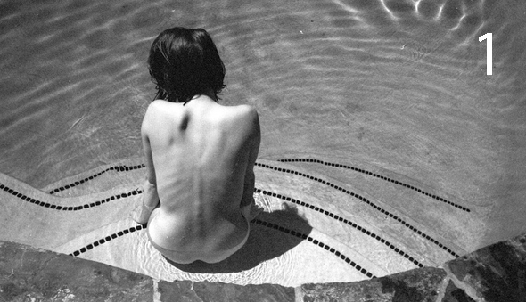 Bare back of someone sitting in a pool.
