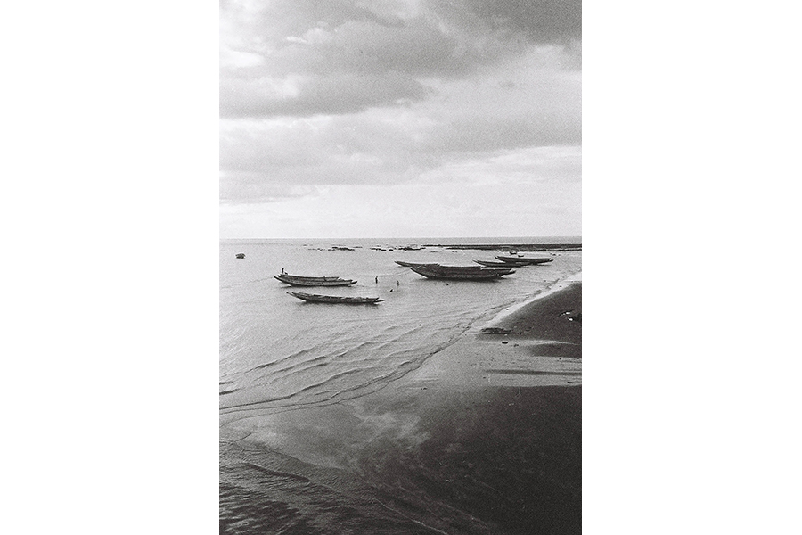 Landscape photo in black and white of a few boats off the coast. 