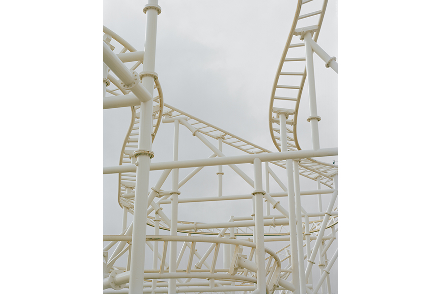 Photograph of a twisted mass of white railing against a white sky; the shapes suggest the structure might be a roller coaster, but there's nothing to clearly put the image in the context of a larger scene