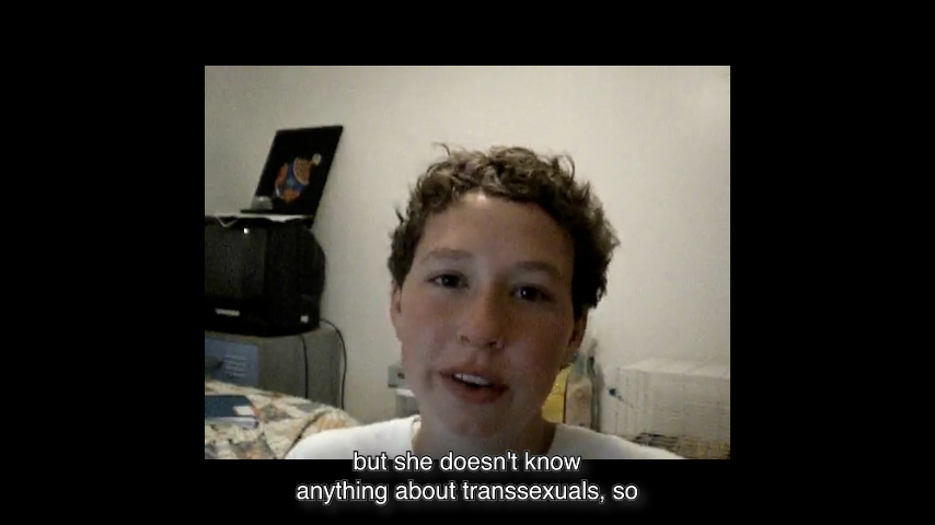 Webcam still image of a boy facing the camera. Subtitles: “...but she doesn’t know anything about transexuals, so…”
