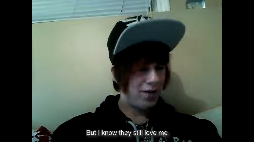 Webcam still image of a boy facing the camera. Subtitles: “But I know they still love me.”
