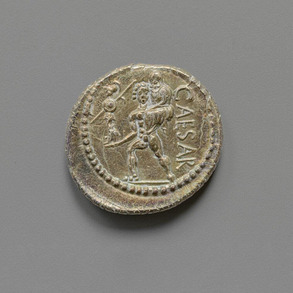 Roman coin showing Aeneas carrying his father on his back, the word CAESAR 